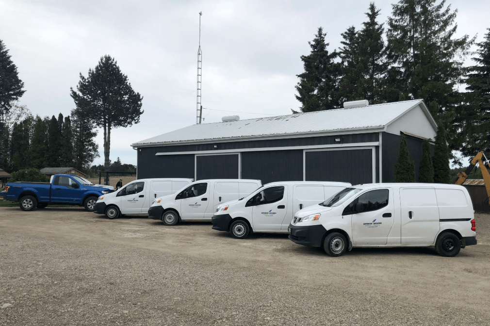 Fleet of white service vans parked outside a building on a cloudy day.